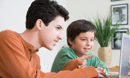 Teen boy helping younger computer (low res)