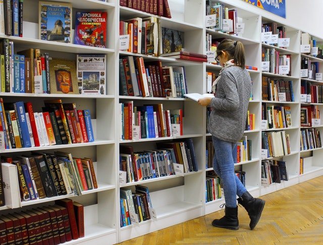 College Books Piled Over a Student's Head